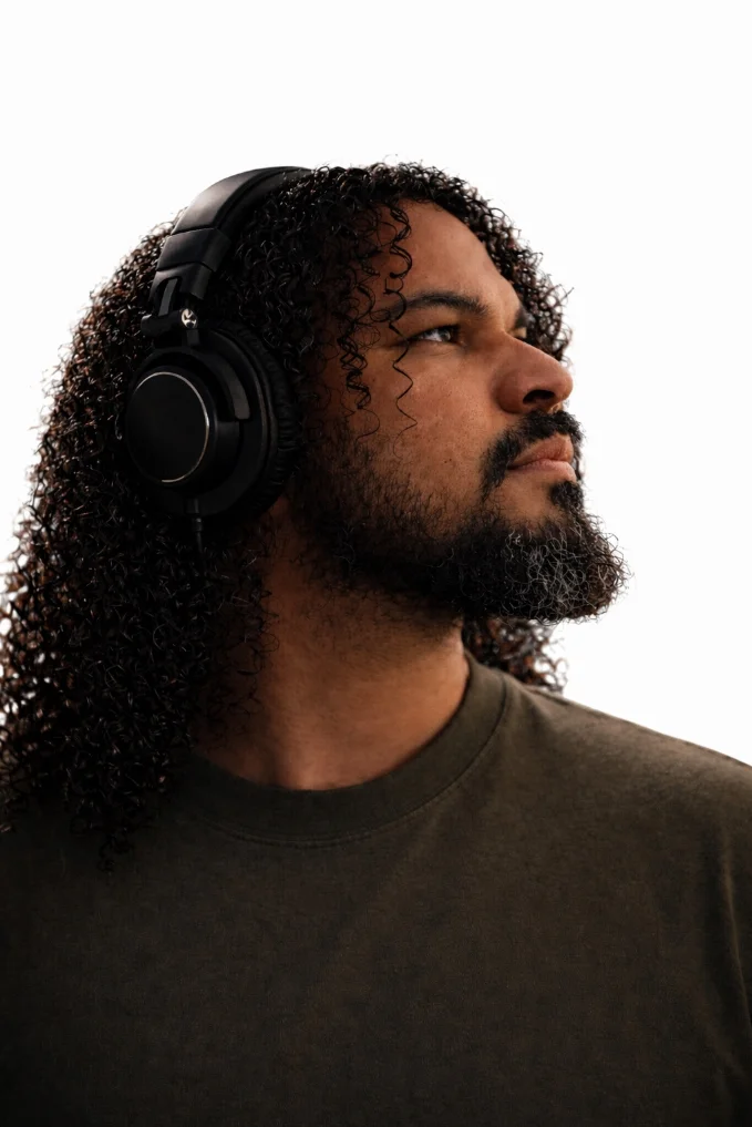 A close-up portrait of a man wearing headphones and looking to the side.