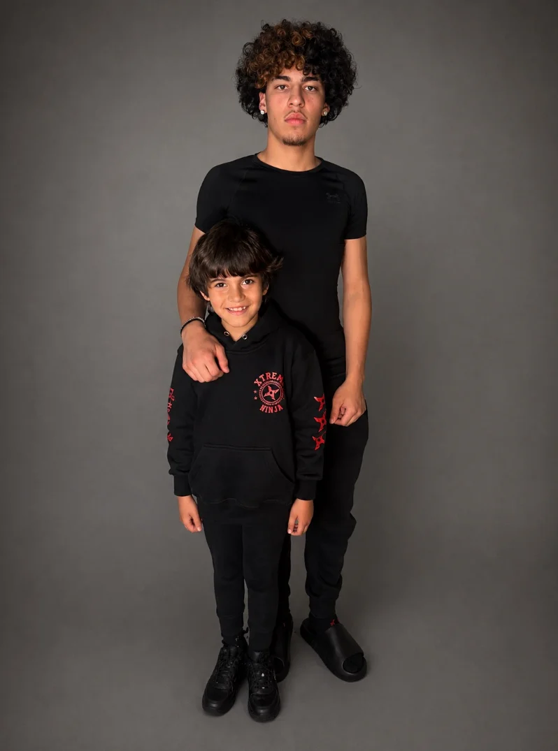 Two young people standing together against a gray studio backdrop.